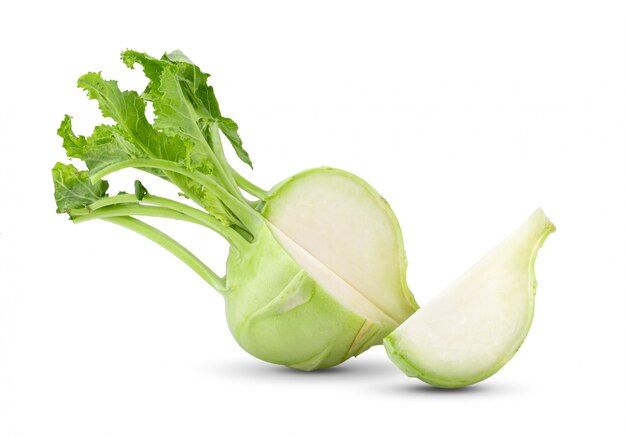 Fresh kohlrabi with green leaves on white wall.