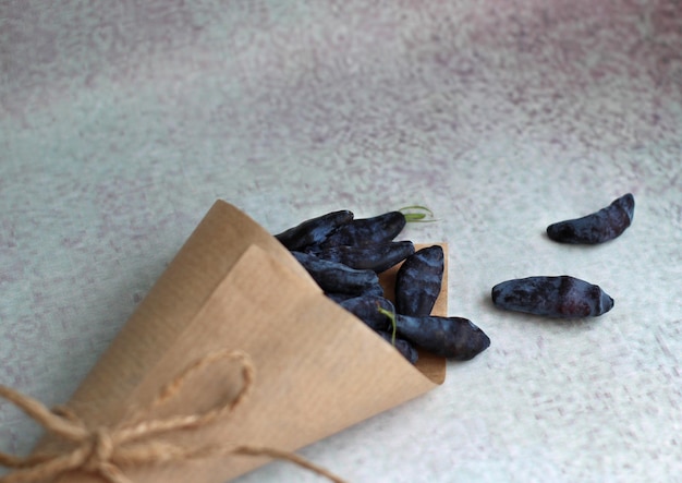 Fresh large honeysuckle berry in a paper envelope on a purple background