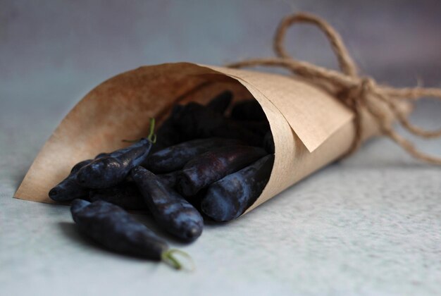 Fresh large honeysuckle berry in a paper envelope on a purple background