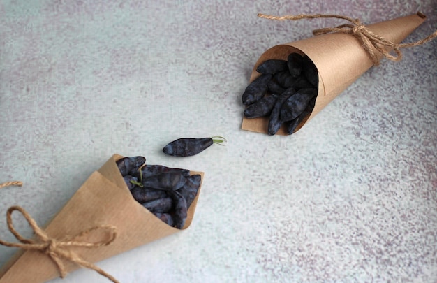 Fresh large honeysuckle berry in a paper envelope on a purple background