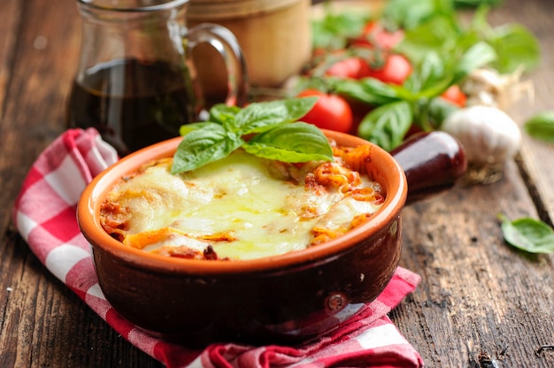 Fresh lasagna in a white container with basil