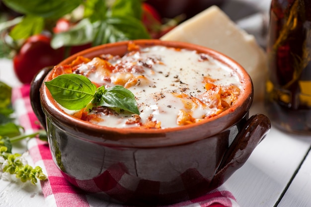 Fresh lasagna in a white container with basil