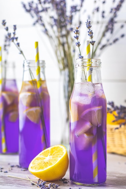 Fresh lavender violet cocktail with lemon and ice drink bottles glass on a light old rustic style selective focus shallow depth of the field