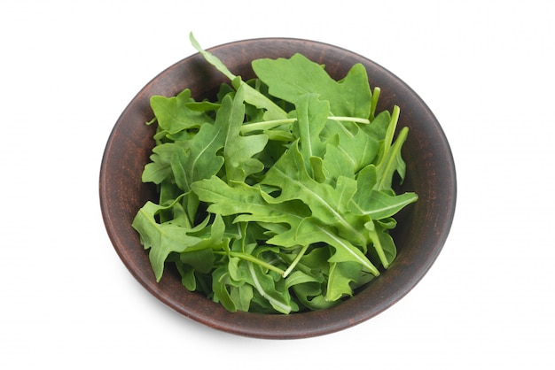 Fresh leaves of arugula in ceramic brown bowl isolated 