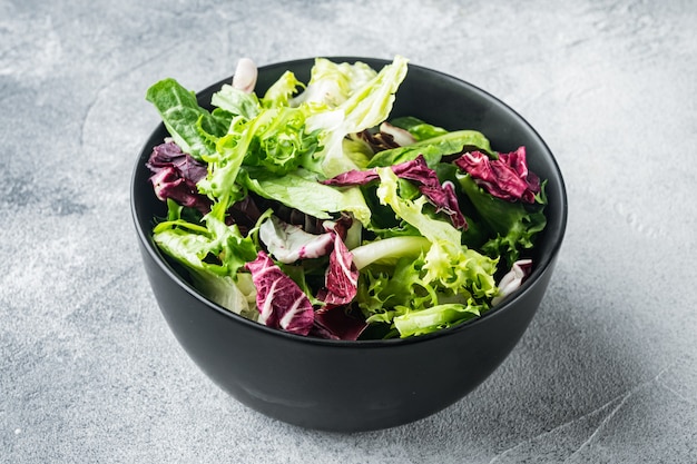 Fresh leaves of different lettuce salads, on gray background