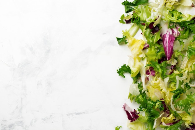 Foto foglie fresche di insalata diversa su priorità bassa di pietra bianca