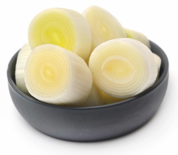 Fresh leek stem chopped in a bowl over white background