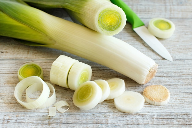 Fresh leeks whole and sliced on a wooden table