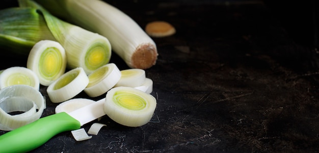 Fresh leeks whole and sliced on a wooden table