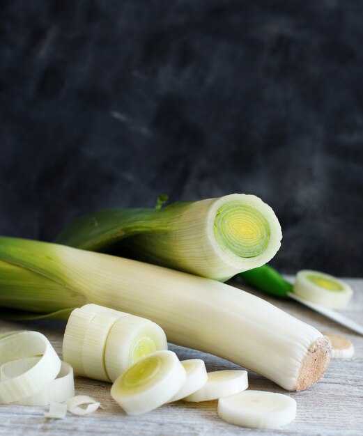 Fresh leeks whole and sliced on a wooden table