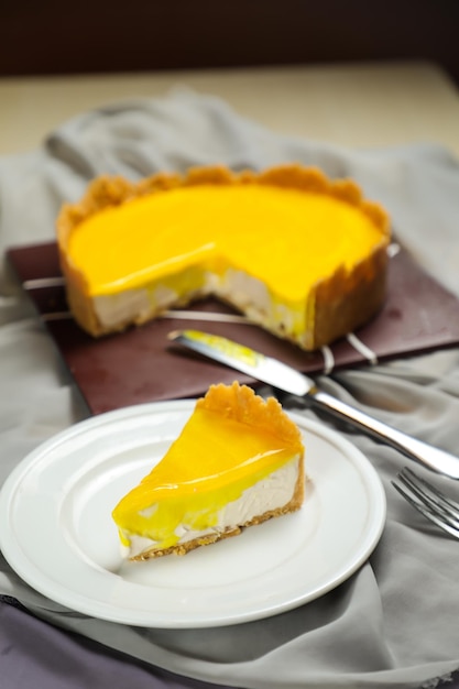 Fresh lemon cheesecake slice with fork and knife served in plate isolated on napkin top view cafe bake food