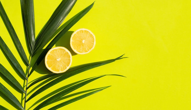 Fresh lemon with green leaves on green surface