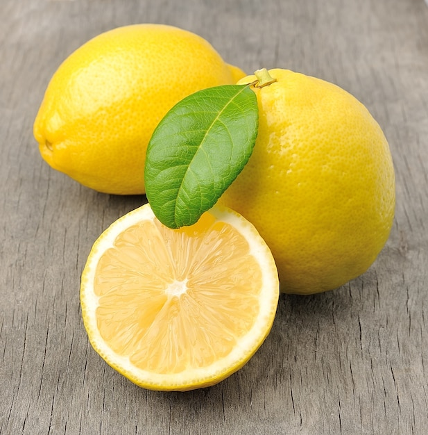 Свежий лимон с листьями на деревянном столе.