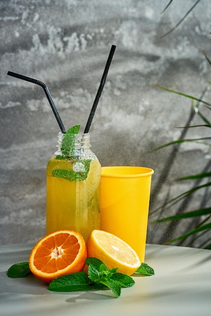 Свежий лимонад в составе с апельсином и бумажным стаканчиком серый фон