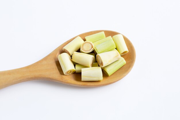 Fresh lemongrass cut pieces on wooden spoon on white