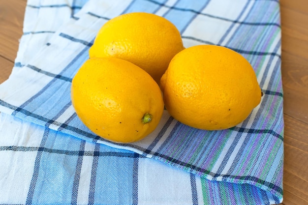 Fresh lemons on a blue cotton napkin on a wooden kitchen table Bright ripe juicy fruit