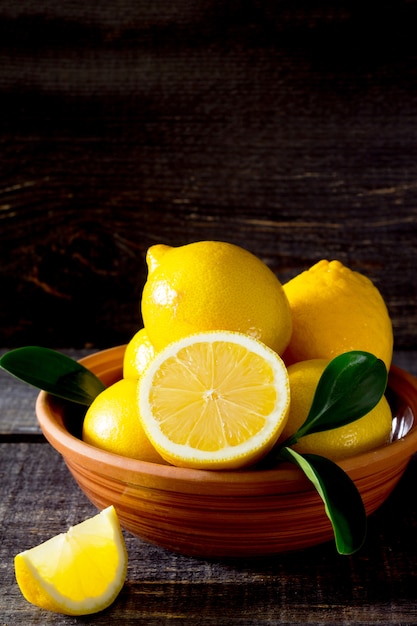 Fresh lemons in a bowl on a wooden table