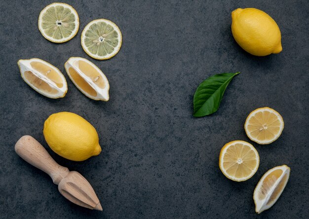 Fresh lemons and  lemons leaves on dark stone background.