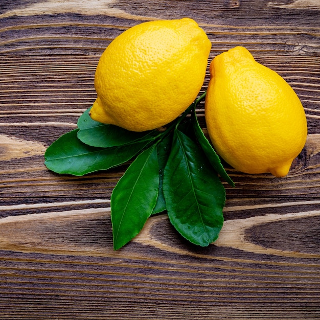 Fresh lemons and  lemons leaves on shabby wooden background.