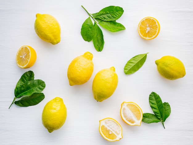 Fresh lemons and  lemons leaves on white wooden background.