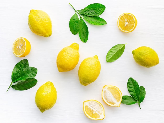 Fresh lemons and  lemons leaves on white wooden background