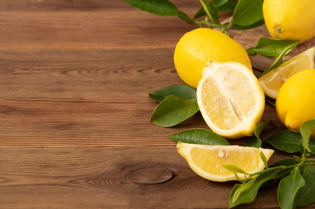 Fresh lemons on rustic wooden table. Citrus fruits with leaves.