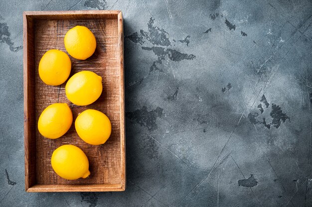 Set di limoni freschi, in una scatola di legno, su sfondo grigio, vista dall'alto piatto laici, con copyspace e spazio per il testo