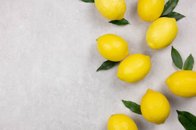 Fresh lemons with leaves on light gray concrete surface