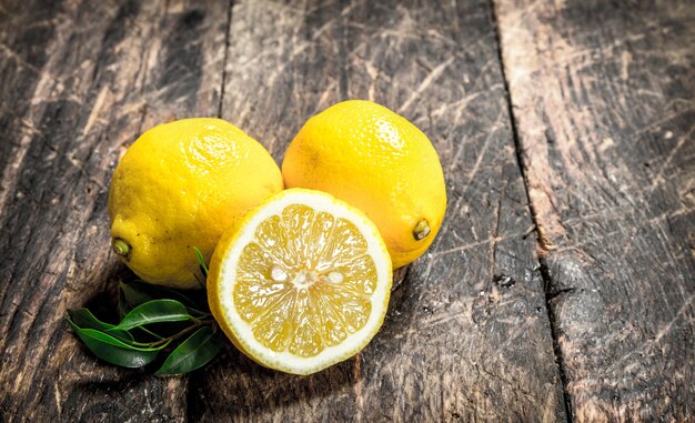 Foto limoni freschi con foglie. su uno sfondo di legno.