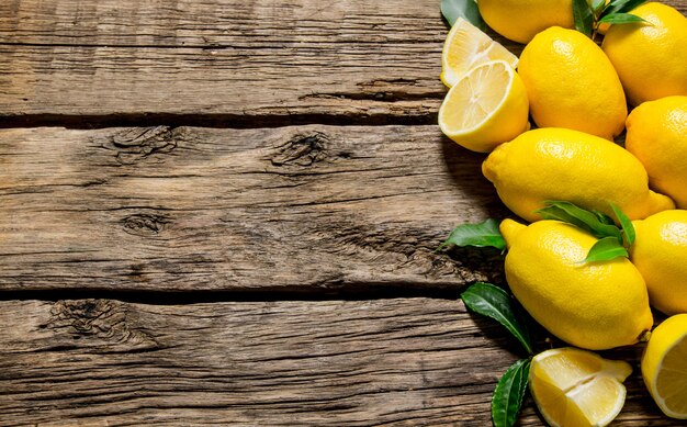 Fresh lemons with leaves on wooden table. Top view