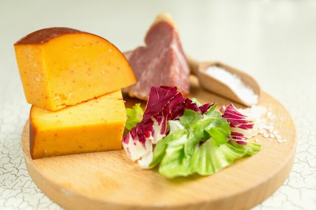 Fresh lettuce, cheese, ham and sea salt on a cutting board