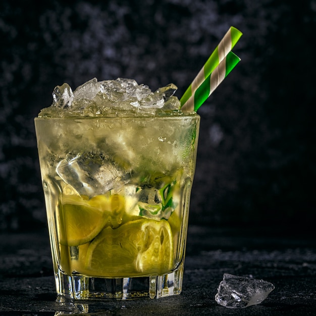 Cocktail di lime fresco con ghiaccio su oscurità.