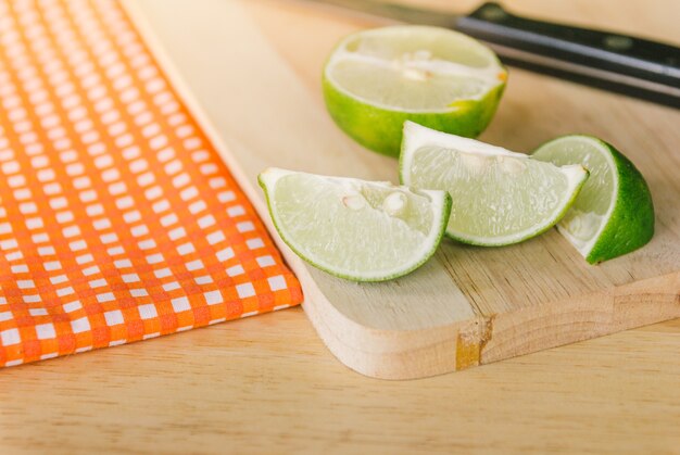 Photo fresh lime slice on wooden desk with classic orange plaid fabric background