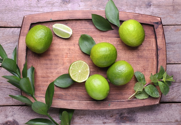 Fresh limes and board on wooden surface