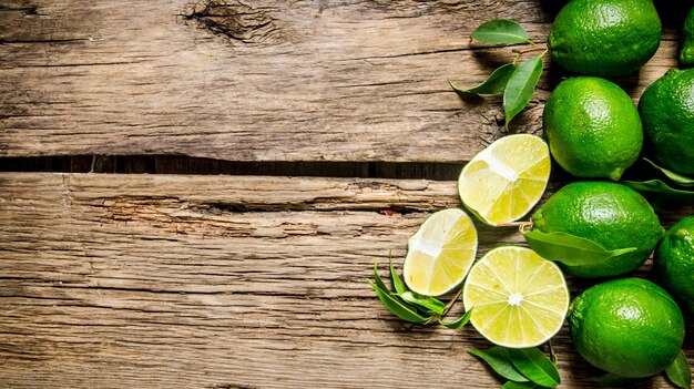 Photo fresh limes with leaves. on wooden table.