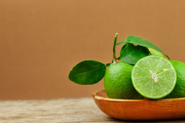 Fresh limes in wooden bowl on wooden background