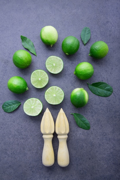 Fresh limes and wooden juicer on white background. Top view with copy space