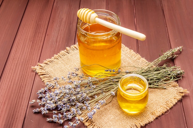 Fresh liquid honey in glass jars with a wooden honey dipper