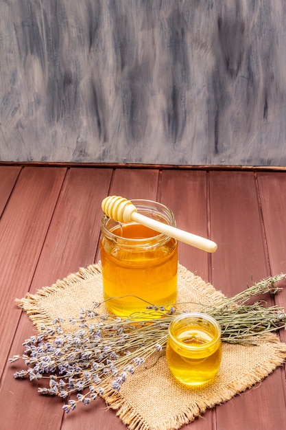 Fresh liquid honey in glass jars with a wooden honey dipper