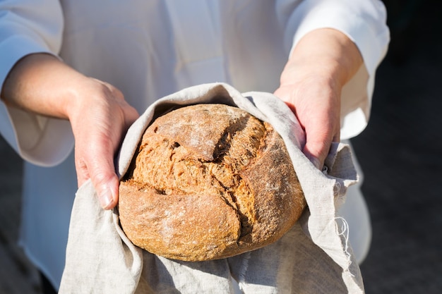 Fresh loaf of homemade rye bread in woman hands