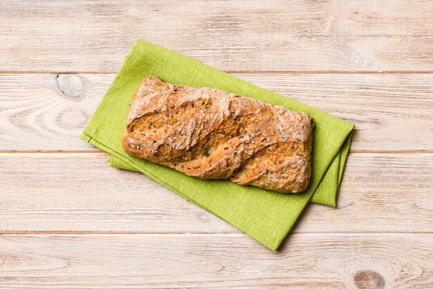 Fresh loaves of bread with wheat and gluten on a colored table bread on napkin on rustic background fresh bread top view