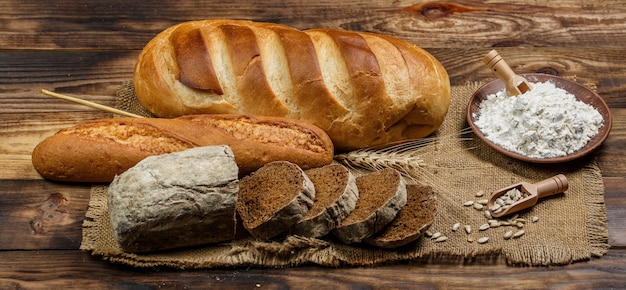 Fresh loaves of bread with wheat and gluten on a wooden table