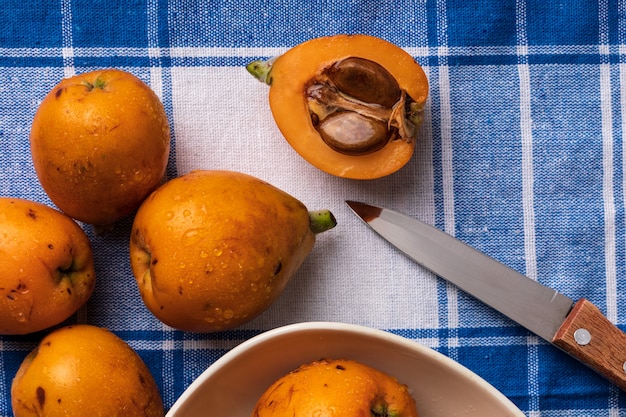 블루 체크 무늬 식탁보 배경에 신선한 비 파 (medlars) 소박 하 고 건강 한 외관입니다. 클로즈업입니다.