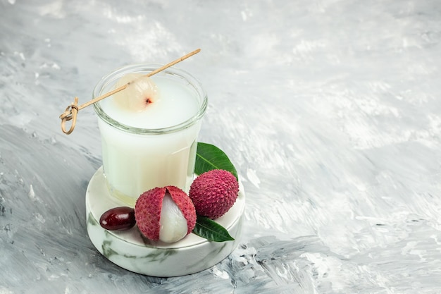 Foto bevanda fresca di litchi e fetta sbucciata su uno sfondo chiaro di frutta tropicale estate in thailandia posto per la vista dall'alto del testo