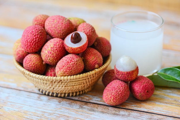 Photo fresh lychee drink and slice peeled with green leaves harvest in basket from tree tropical fruit summer in thailand lychee juice on wooden table