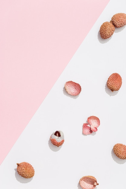 Fresh Lychee fruit on pastel pink white background. Minimal fruit and summer concept. Top view and sunlight