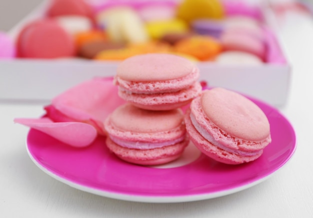 Fresh macaroons on pink plate closeup