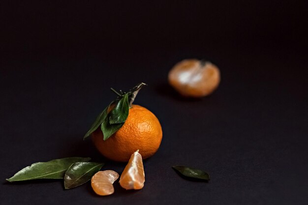 Foto frutta fresca di mandarino con foglie verdi isolate su uno sfondo nero