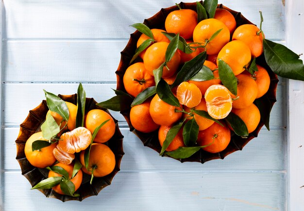 Fresh mandarin oranges fruit or tangerines with leaves in wooden box, top view