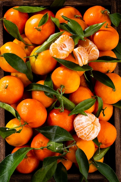 Fresh mandarin oranges fruit or tangerines with leaves in wooden box, top view